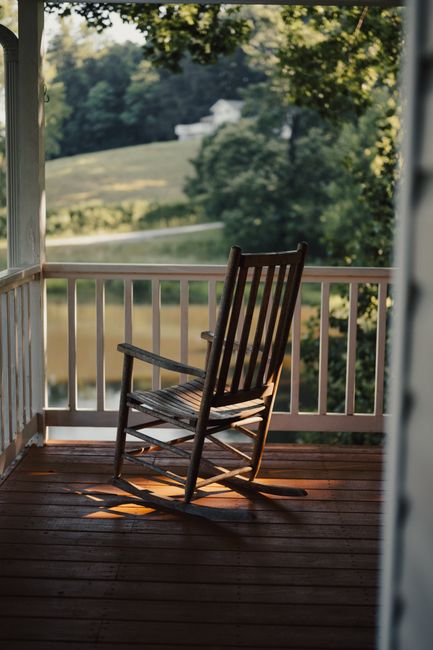 Rocking chair on a covered front porch with a white railing